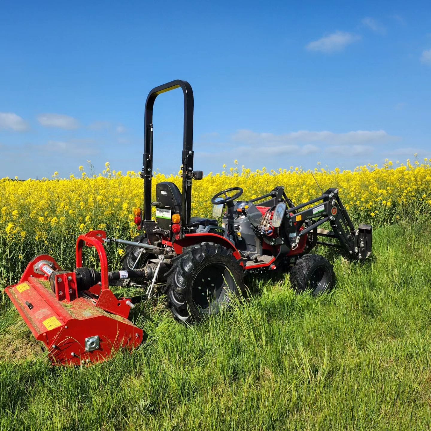 Traktor er gang med at Brakpudsning ved en blomstrende rapsmark