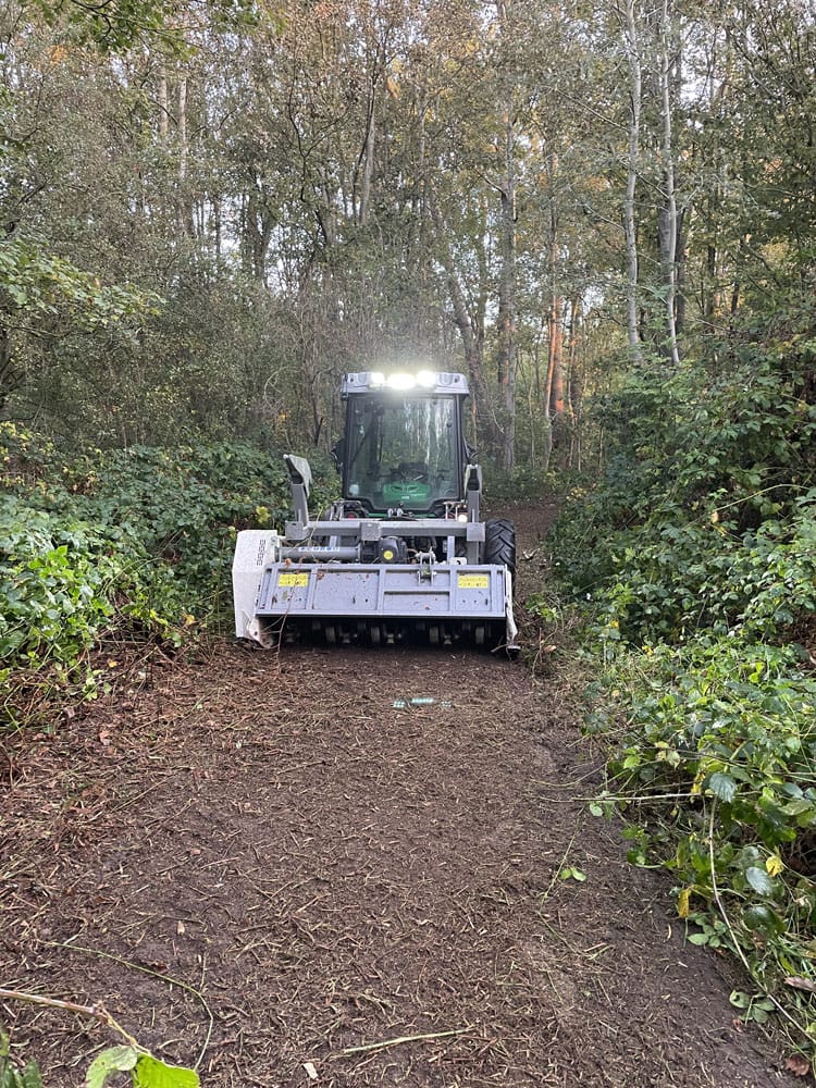 komparktraktor med knuser rydder skovsti for vegetation